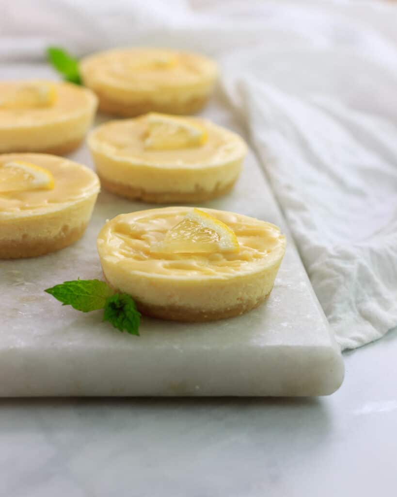 white chocolate lemon cheesecake on a plate atop a marble table