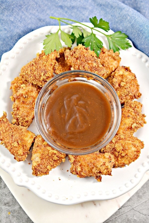 keto chicken nuggets on a plate with a dip in the center atop a kitchen counter