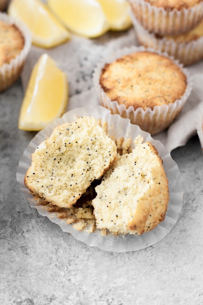 keto-lemon-poppy-seed-muffins-split-in-half-with-a-lemon-wedge-and-muffins-in-the-background