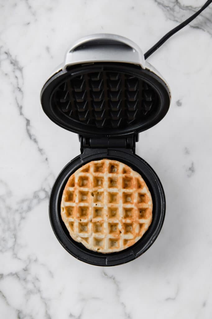 chaffle being cooked on a waffle iron