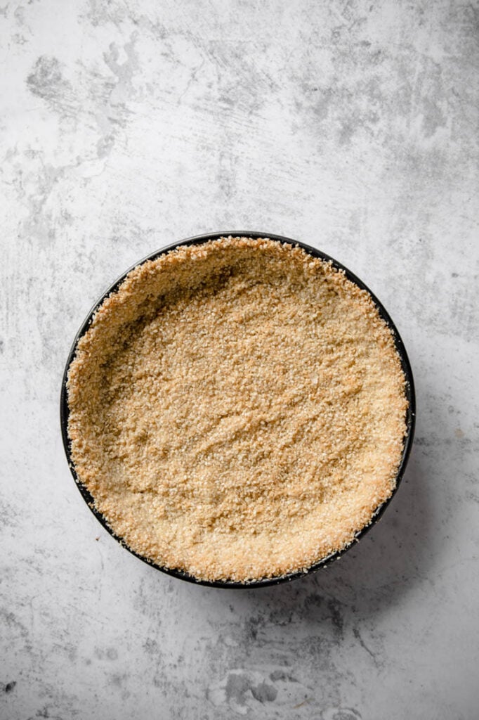 baked keto key lime pie crust on a springform pan atop a marble kitchen counter