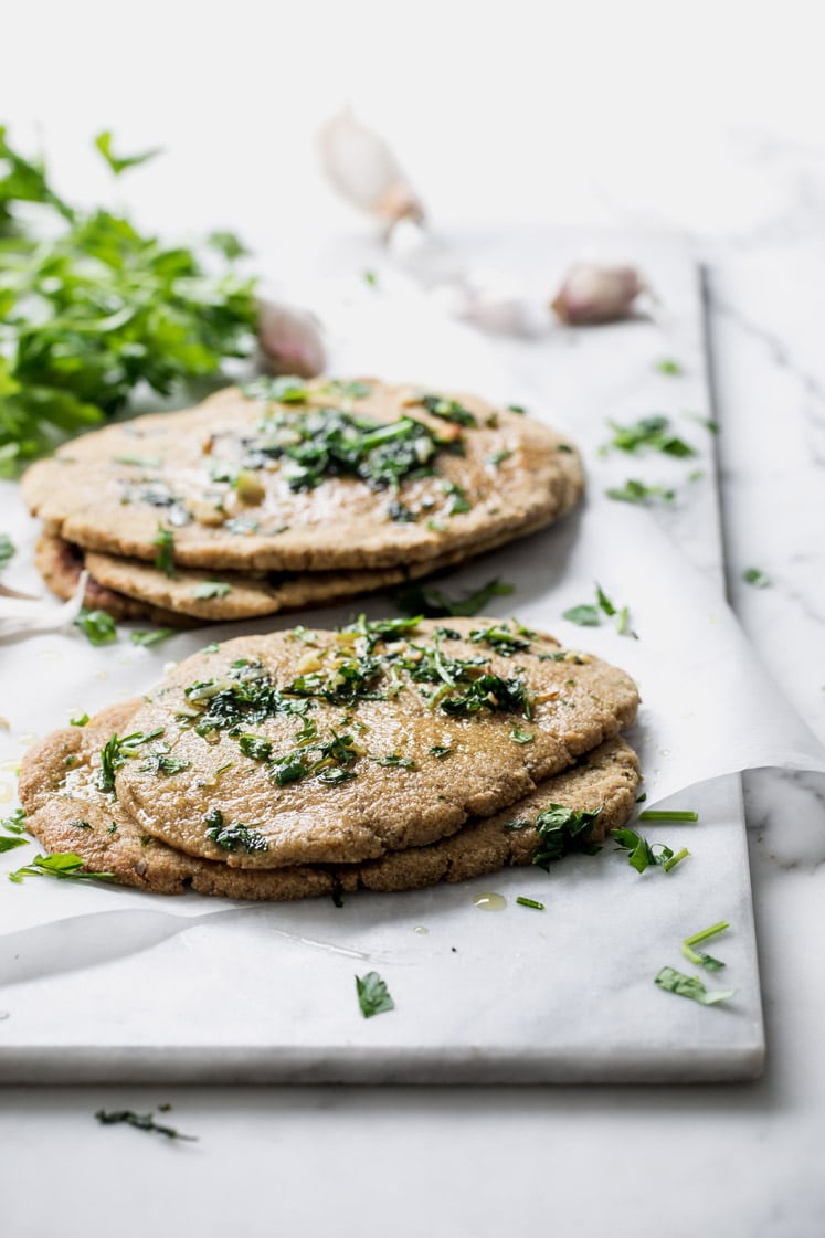2 stacks of nut free keto naan bread topped with chopped parsley atop a marble counter