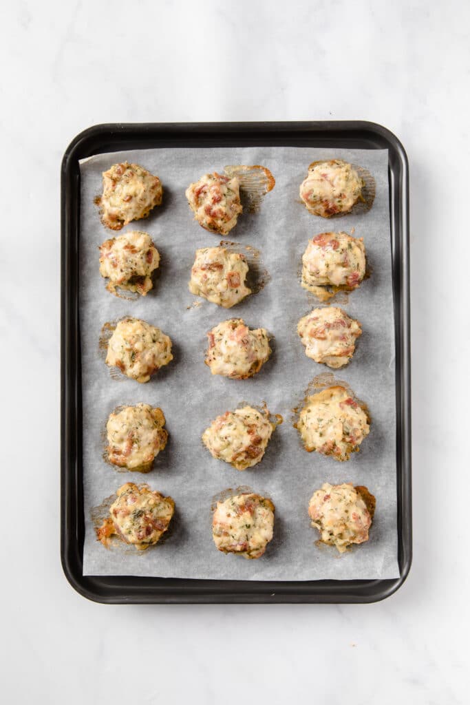cooked popper balls placed on top of a baking sheet
