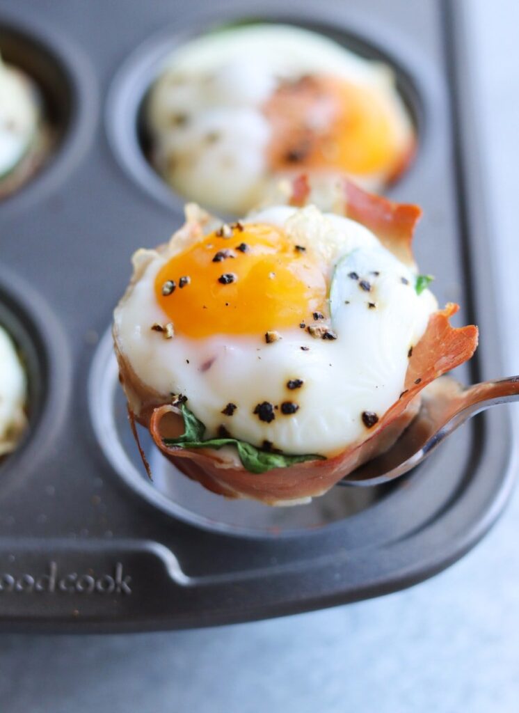 prosciutto egg cups on a baking tray atop a kitchen counter