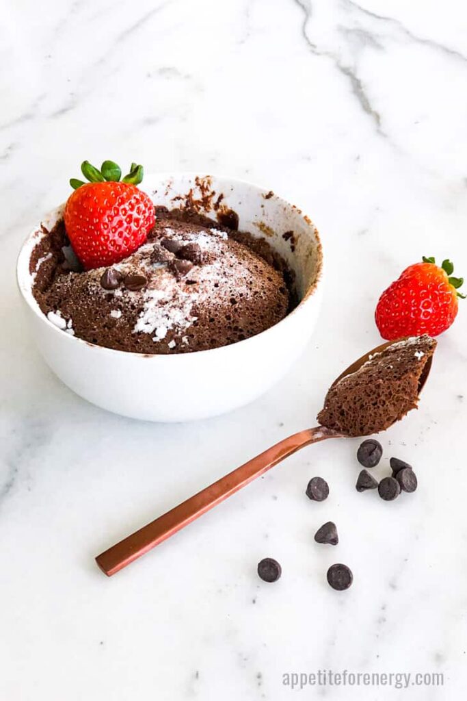 keto chocolate mug cake topped with strawberries atop a marble kitchen counter