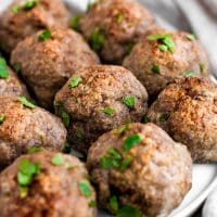 10 keto meat balls on a plate atop a marble kitchen table by real balanced