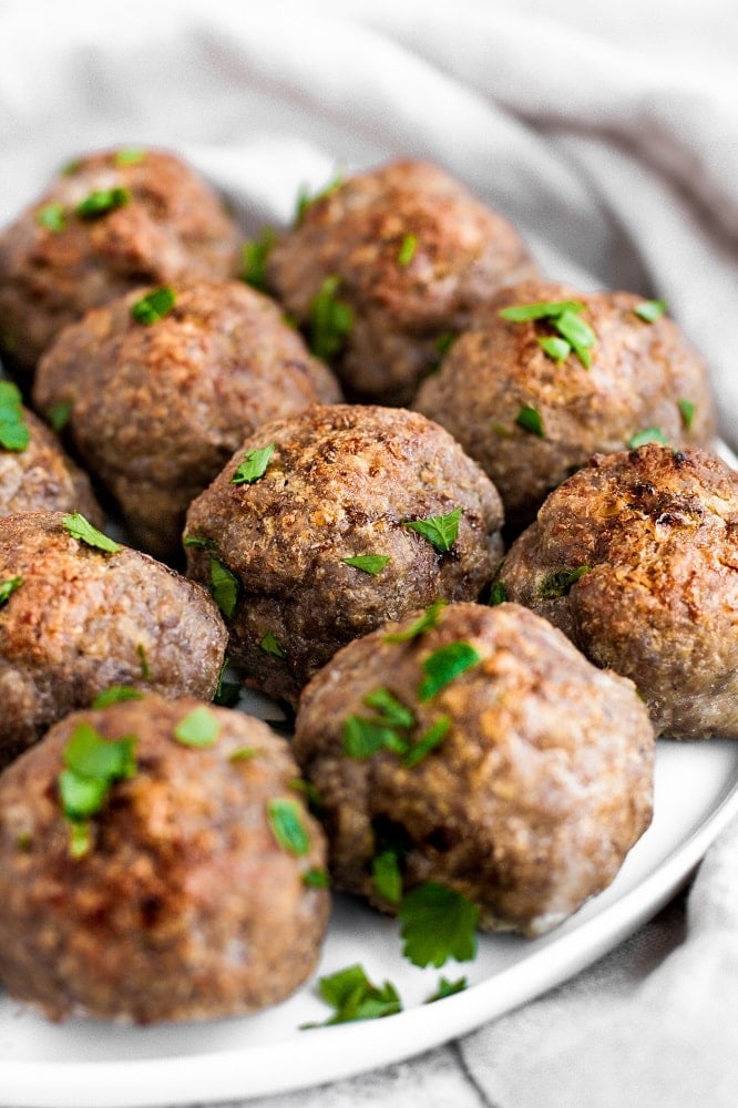 10 keto meat balls on a plate atop a marble kitchen table by real balanced