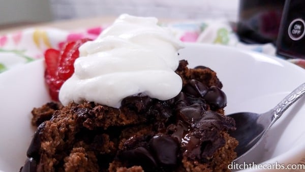 close-up image of chocolate lava cake topped with whipped cream in a bowl