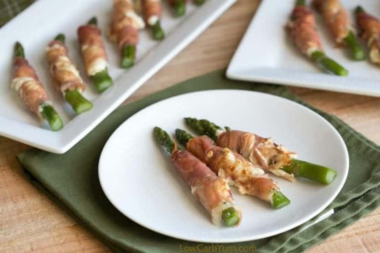 prosciutto wrapped bacon asparagus cream cheese on a plate atop a wooden counter