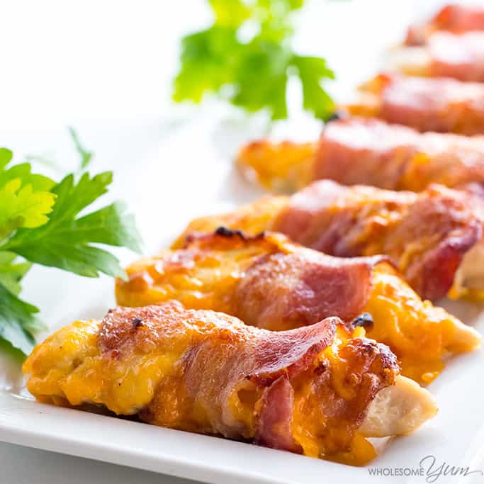 close-up shot of bacon wrapped chicken tenders on a plate atop a kitchen counter