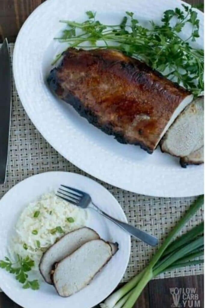 Char Siu Chinese BBQ Pork with cauliflower salad on a plate atop a wooden table