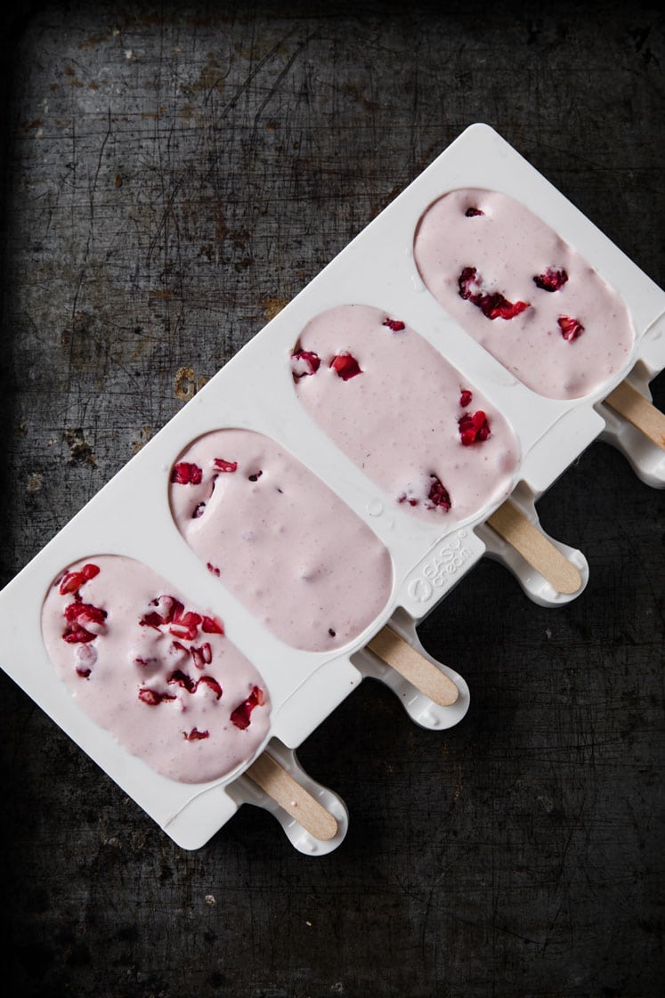 berries and cream poured in popsicle mould atop a marble kitchen counter