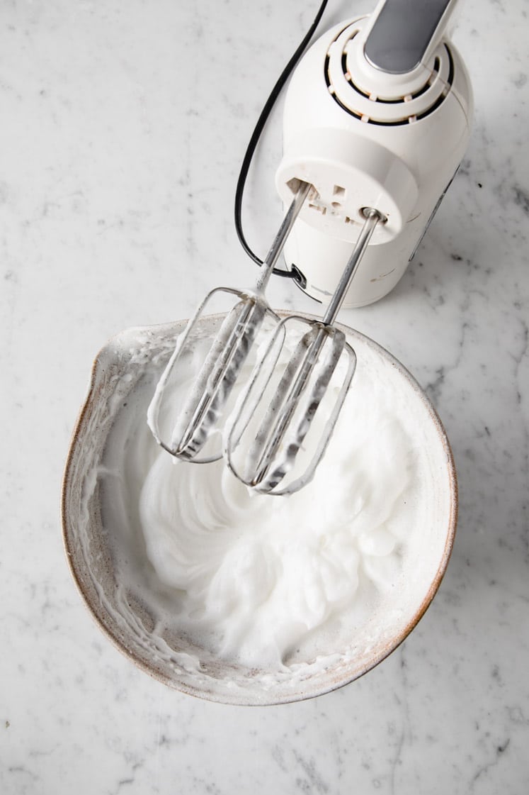 egg whites mixed by an electric mixer in a mixing bowl