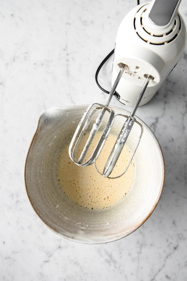 egg yolks and monk fruit sweetener mixed by an electric mixer in a mixing bowl atop a marble kitchen counter