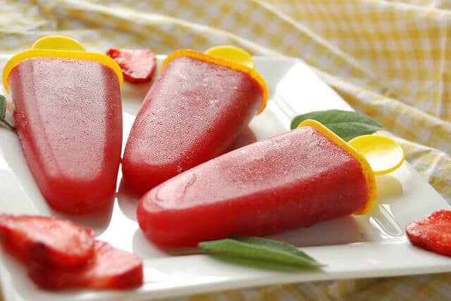 keto berry recipes: 3 strawberry popsicles lined horizontally on a square plate