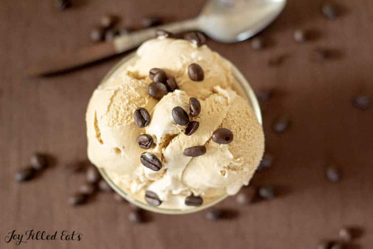 overhead image of a bowl of keto coffe ice cream topped with coffee bits atop a wooden table