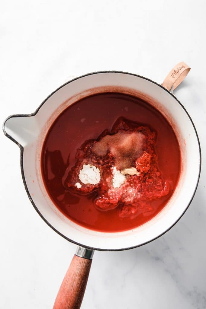 overhead view saucepan containing tomato puree, water, and other spices