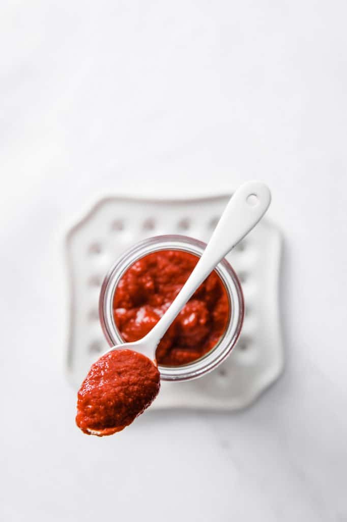 overhead shot of a teaspoon and jar full of homemade low carb ketchup
