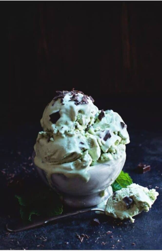 a bowl of Low-Carb Mint Chocolate Chip Ice Cream atop a wooden table
