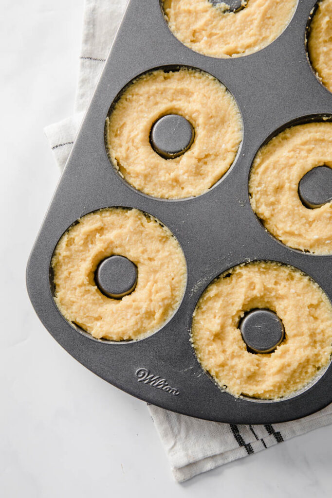 donut batter in a donut pan atop marble kitchen table