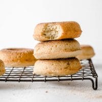 close-up image of 3 nut-free keto donuts stacked on top of each other resting on a wire rack atop a marble kitchen counter