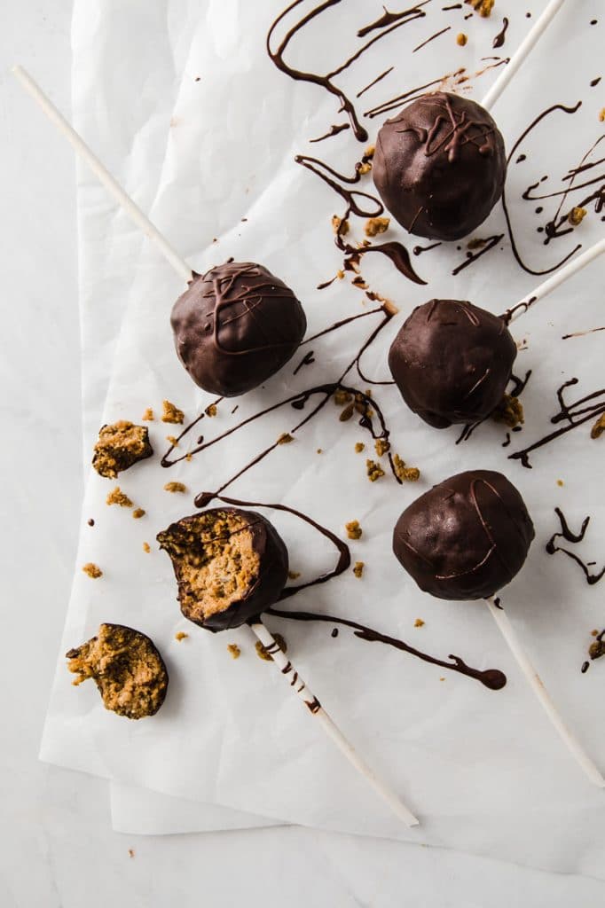 overhead image of a half eaten pumpkin pie cake pops on a parchment paper atop a marble kitchen table