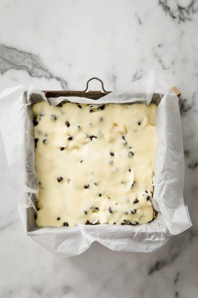 overhead image of a pan of keto magic bars with the top covered with sweetened condensed milk
