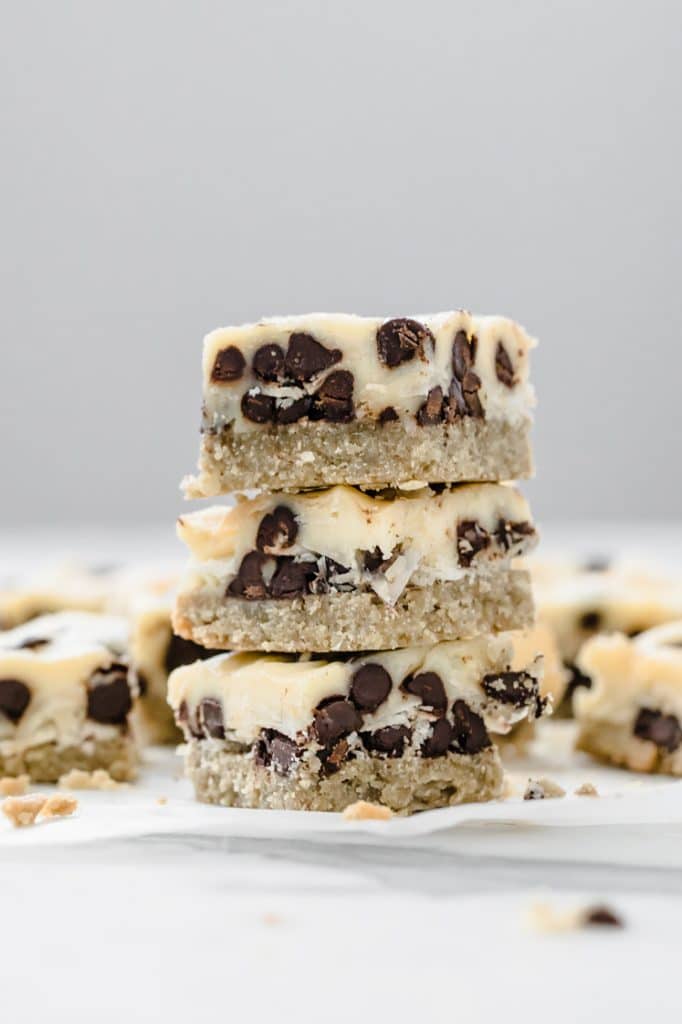 close-up image of 3 keto magic bars stacked on top of each other resting atop a marble kitchen counter