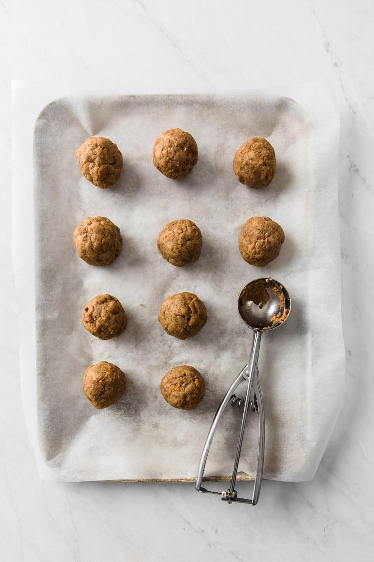 pumpkin pie cake rolled into small balls on a parchment paper-lined baking sheet