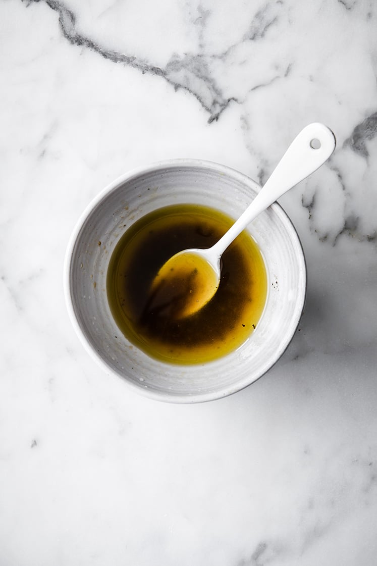 a bowl of thai coconut chicken dressing with a spoon atop a marble kitchen counter