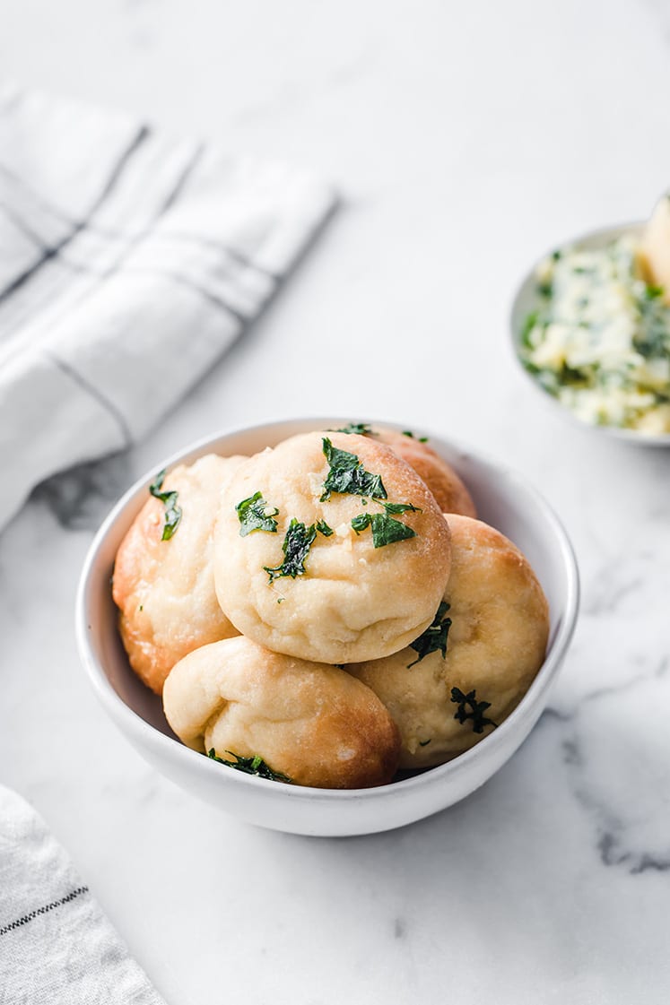a bowl full of keto garlic dough balls atop marble kitchen counter