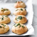 a baking pan lined with parchment paper filled with keto garlic dough balls
