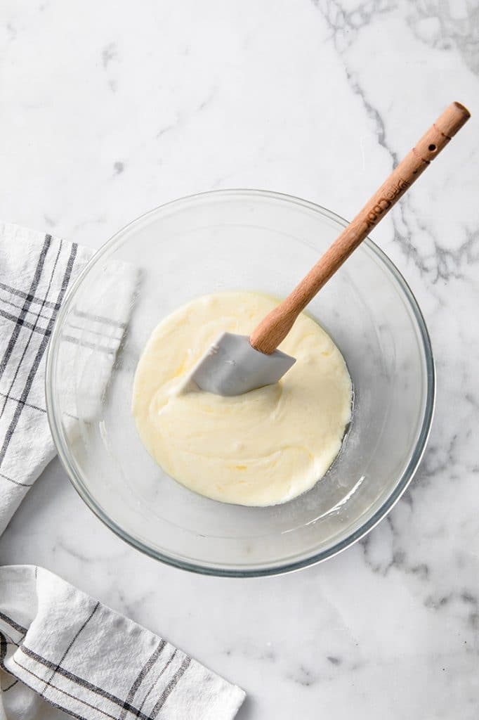 melted mozzarella cheese being stirred by a rubber spatula atop a marble kitchen table