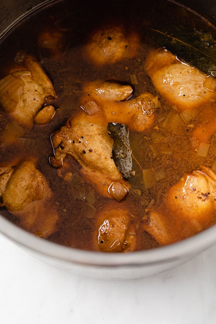 chicken adobo in an instant pot atop a marble kitchen table