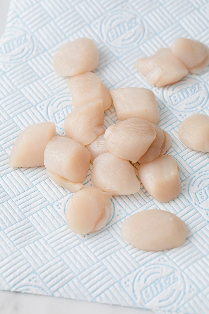 raw scallops being dried off on a paper towel