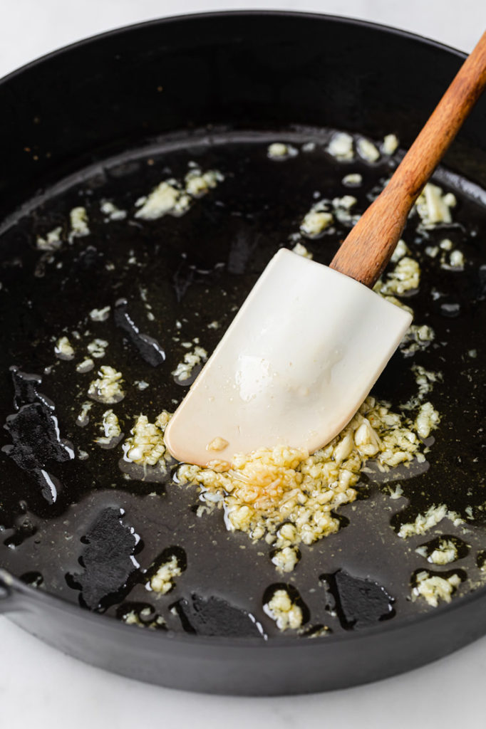 garlic being sautéed with melted butter in a pan
