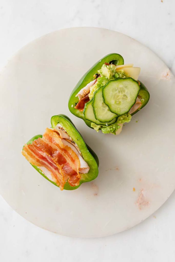 green bell pepper sandwich with bacon, turkey, cheese, and cucumber slices