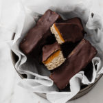 angled overhead image of a baking pan filled with nut-free keto twix bars atop a marble kitchen counter