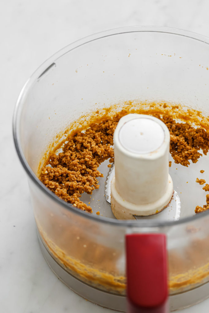 pork rind crumbs in a food processor atop a marble kitchen counter