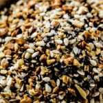 a bowl of everything bagel seasoning atop marble kitchen counter.