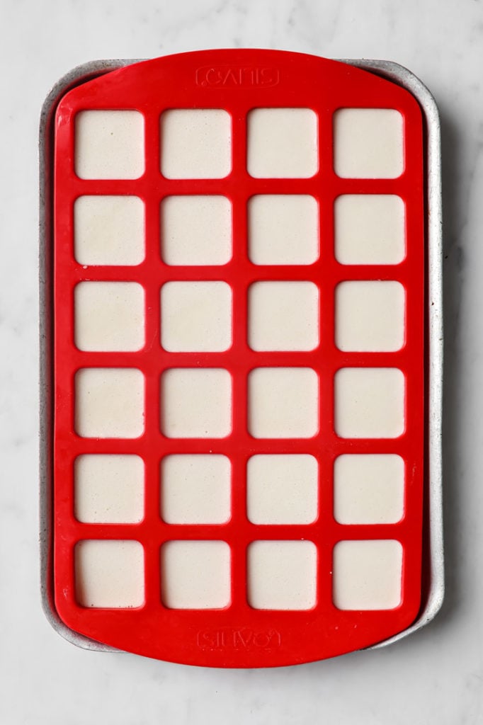 marshmallow mixture poured in a square shaped silicone mold atop a marble kitchen counter