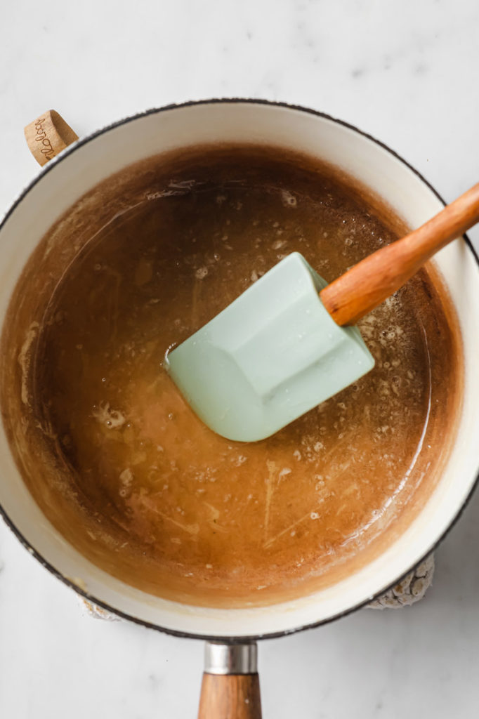 gelatin being stirred by a rubber spatula in a saucepan