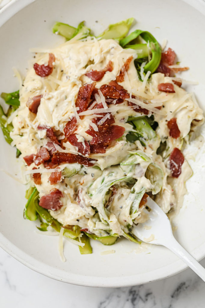 overhead shot of asparagus pasta with fork white in white bowll