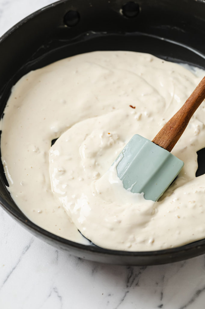 preparing cream sauce in skillet with rubber spatula