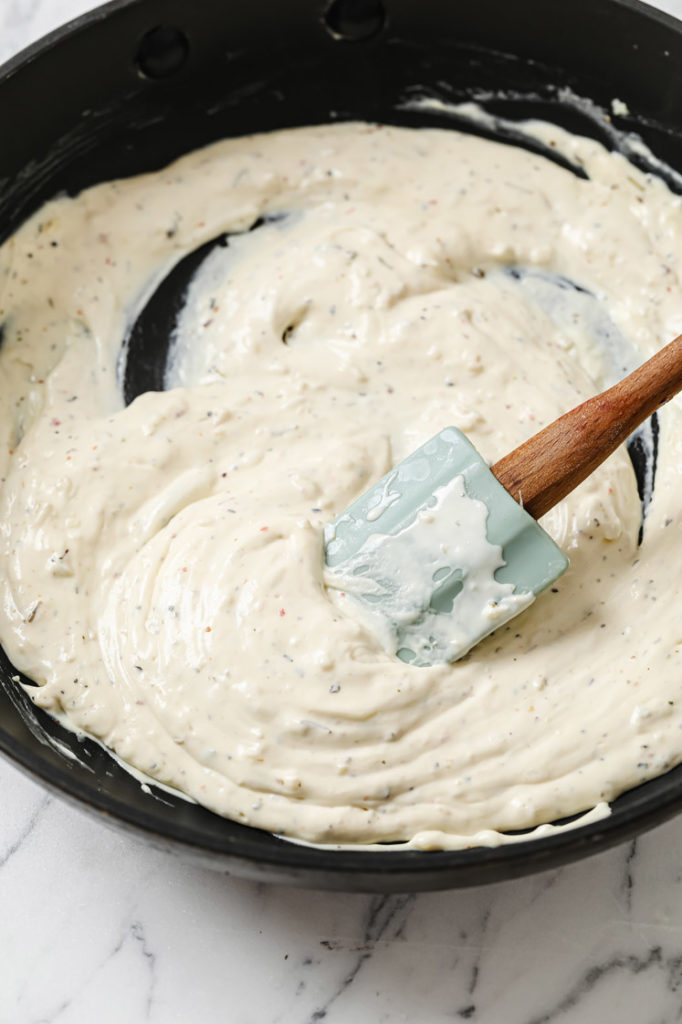 cream sauce being stirred in skillet with rubber spatula