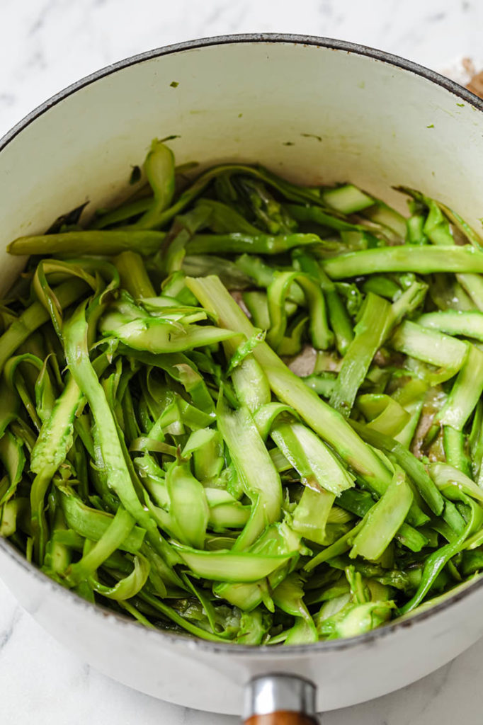 asparagus noodles in large pot being cooked to soften