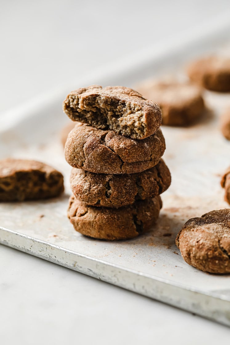 Side close-up shot of Low-Carb Snickerdoodle Cookies stacked together, resting on a baking pan. The top cookie appears to be bitten and shows the inside of the cookie.