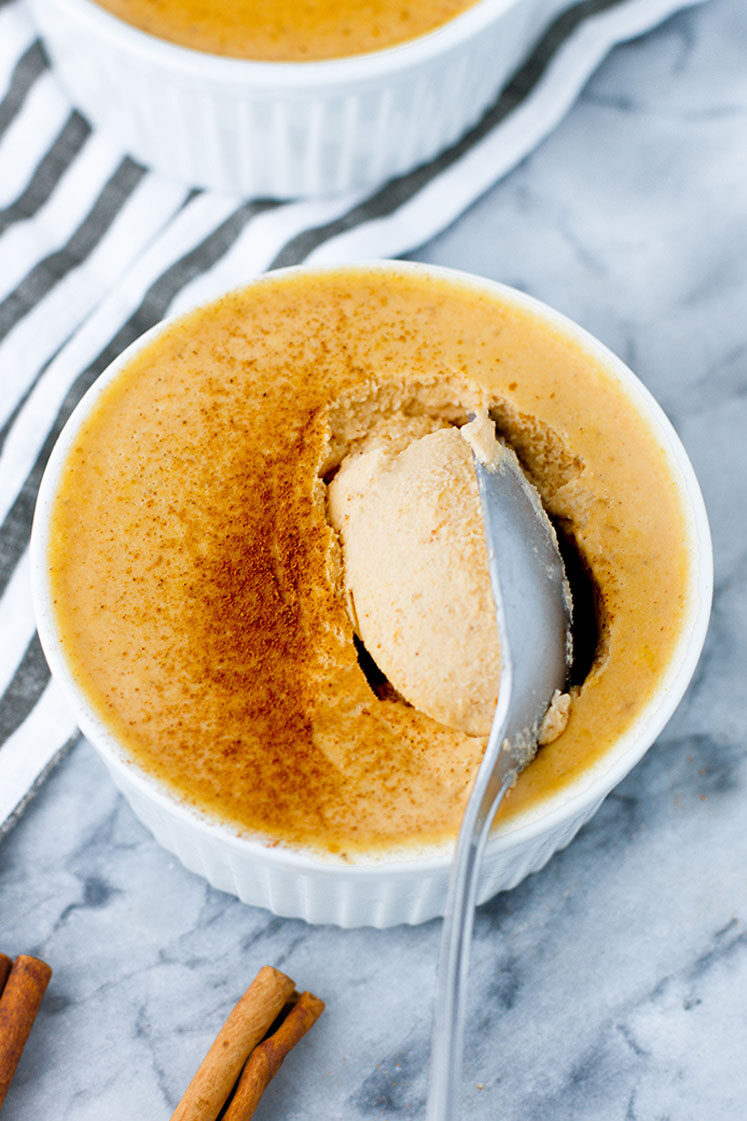 Close-up shot of Pumpkin Pie Panna Cotta being scooped by a spoon atop a marble kitchen counter