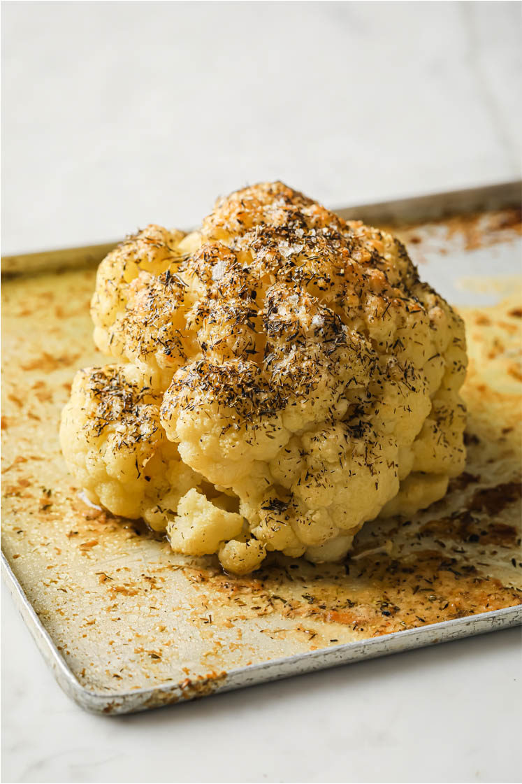 Side shot of the cooked Buttery Roasted Cauliflower on a baking pan atop a marble countertop