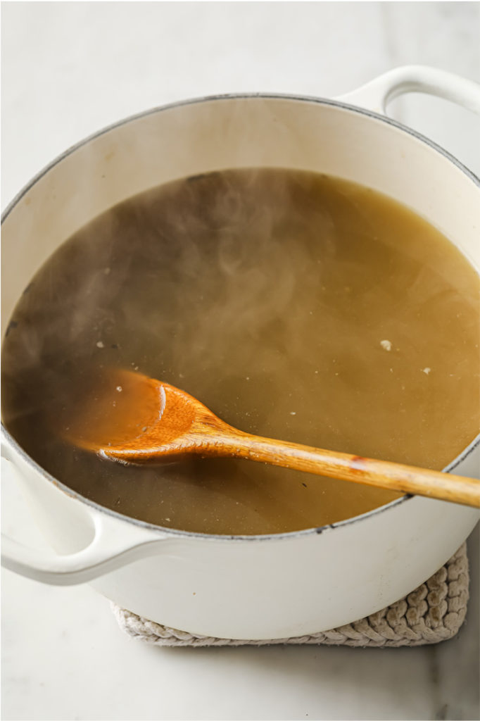 Overhead shot of pot of stock with a wooden spoon